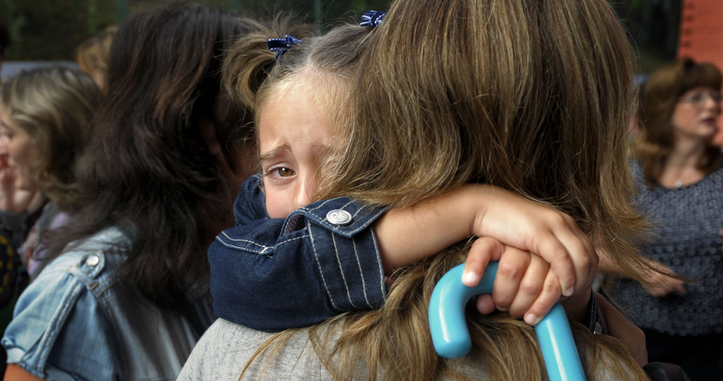 Una niña se abraza a su madre en su primer día de clase.