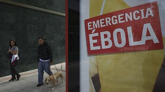 Una pareja pasea ante un cartel sobre la emergencia del ébola.
