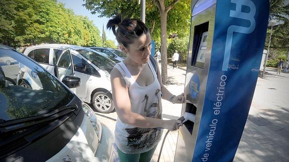 Una mujer recarga su vehículo eléctrico.