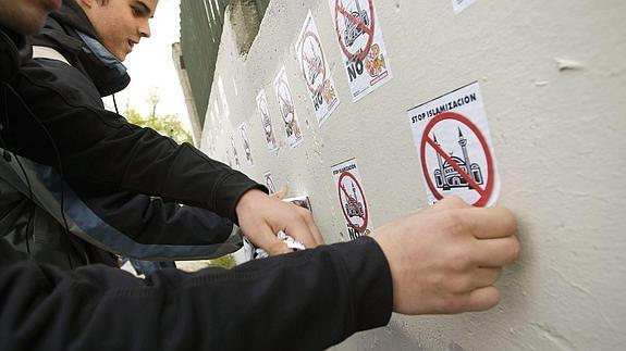 Varios alumnos de un instituto quitan pegatinas xenófobas.