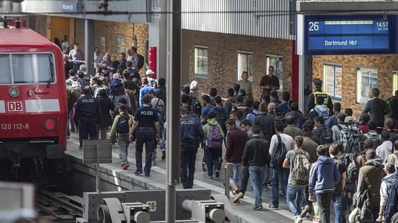 Varios refugiados procedentes de Budapest son escoltados por la Policía mientras se dirigen a un tren con destino a Dortmund.