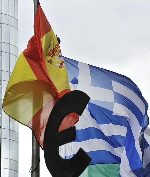 Banderas de España y Grecia ondean ante la estatua que sostiene el símbolo del euro frente a la sede del Parlamento Europeo en Bruselas. 