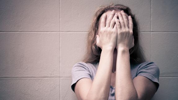 Una mujer se cubre la cara con sus manos.