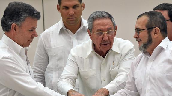 Santos y 'Timochenko' se estrechan la mano en presencia de Raúl Castro. 