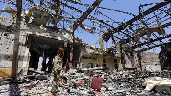 Un hombre inspecciona los restos del edificio destruido por el bombardeo de la coalición árabe sobre Saná, en Yemen.