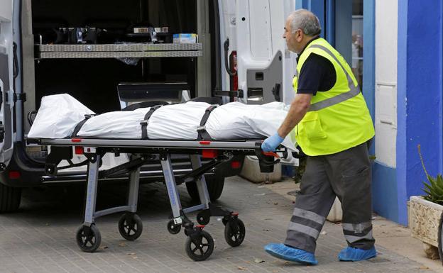 Un empleado de una funeraria saca el cadáver de un hombre que ha fallecido al ser tiroteado. 