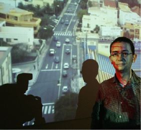 SIGNOS DE CIUDAD. El comisario de la exposición Juan Ramón Barbancho proyecta su sombra sobre una de las videocreaciones. / SEVILLA