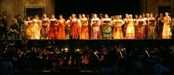 Mariano Rivas, en primer término, dirige la orquesta frente a un escenario colorista y repleto de intérpretesdurante la representación . /JOAQUÍN BILBAO