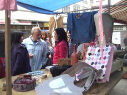 Una mesa con ropa bolsos, en el mercáu. / J. M. PARDO