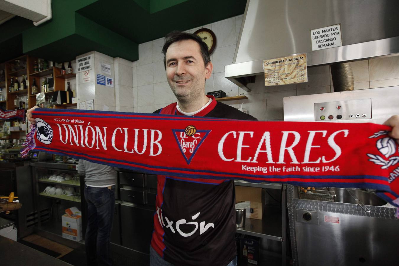 Pablo Carrera, en su bar, con la bandera del Ceares.