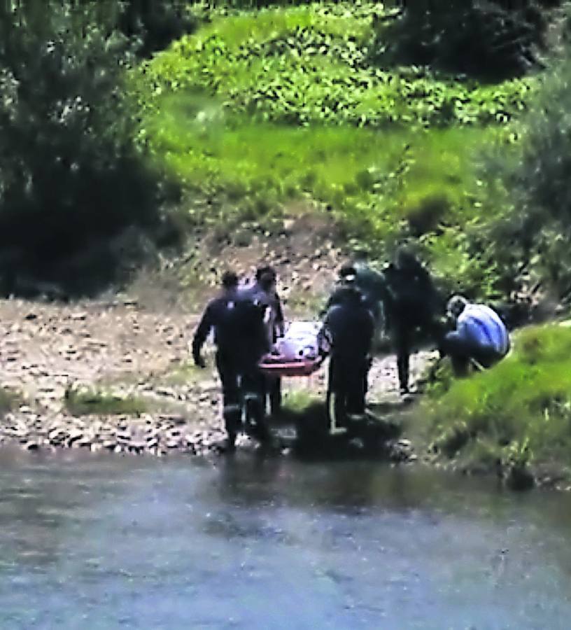Los bomberos trasladan el cadáver a la ribera del Nalón. 