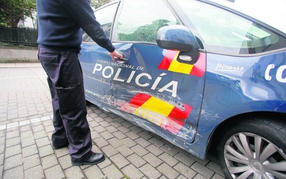 Un agente policial señala los destrozos del coche patrulla tras la persecución.