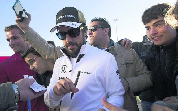 Fernando Alonso firma autógrafos a un grupo de aficionados. 