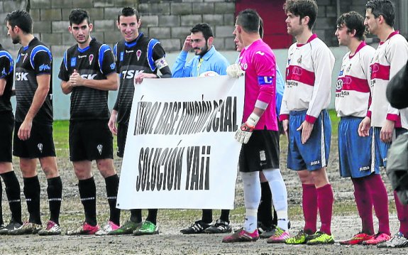 Los jugadores del Gijón Industrial y del TSK Roces despliegan una pancarta en defensa del fútbol base al inicio del partido. :: P. Ucha