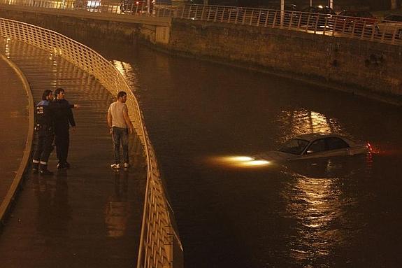 El Rover 75, varios metros río abajo del lugar del accidente, permanece con las luces encendidas, mientras las ambulancias atienden a los ocupantes sobre el puente del río Piles.