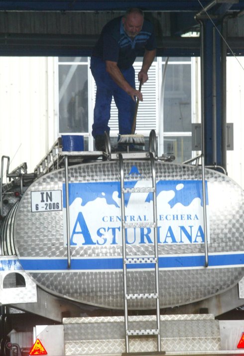 Un trabajador limpia un camión de transporte de leche. 