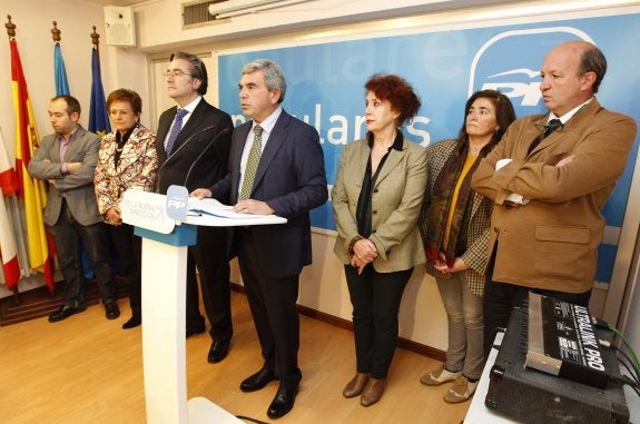 El presidente del PP de Gijón, Mariano Marín, lee la declaración sobre el plan de vías rodeado de miembros de su junta local. 