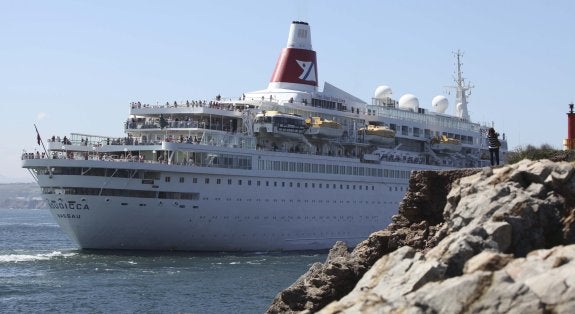 Un buen número de cruceristas se despide de Avilés en la popa del barco en la maniobra de viraje para abandonar la ría avilesina a la altura del faro de San Juan. Algunos curiosos se acercaron a los pedreros para hacer fotografías. 
