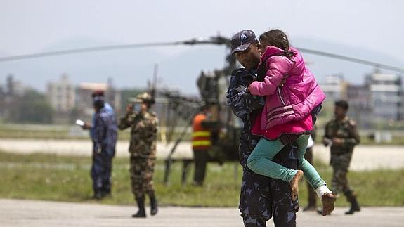 Un soldado nepalí traslada a una niña herida a un helicóptero.