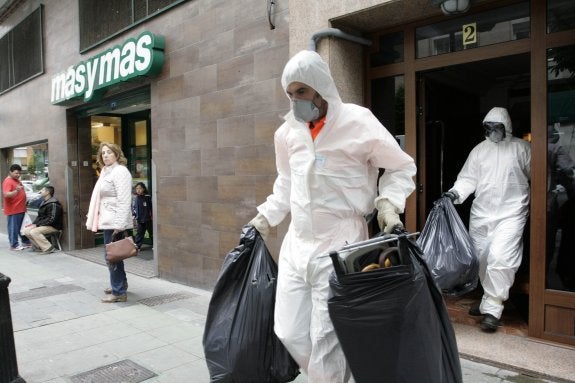 Operarios de Emulsa protegidos con mascarillas sacan bolsas de basura del piso de la calle Aguado. 