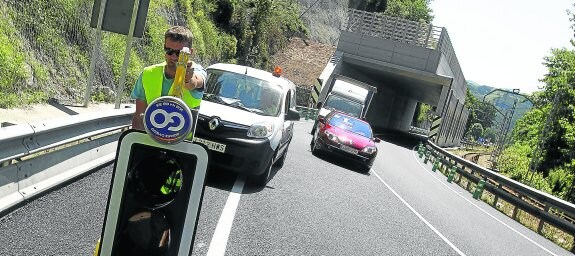 Un operario retira uno de los semáforos provisonales que han regulado el tráfico en la N-634 en Arobes para abrir los dos carriles a la circulación.