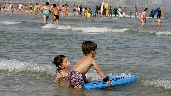 Dos niños disfrutan de una jornada soleada en la playa de San Lorenzo de Gijón. 