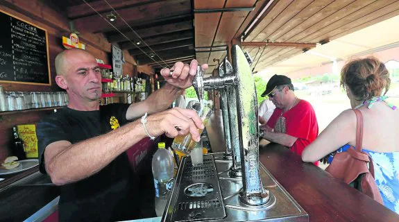Un camarero sirve una caña a unos clientes en el chiringuito Borizu, que ha duplicado su espacio. 
