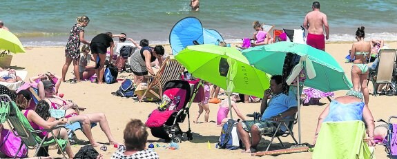 Decenas de gijoneses aprovecharon la festividad local para disfrutar del sol en la playa de San Lorenzo, donde ayer ondeó la bandera verde. 