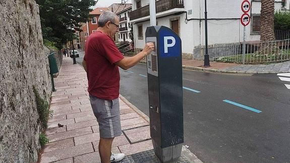 Un usuario sacando su tique en el parquímetro situado en la calle Alfonso IX, en Llanes. 