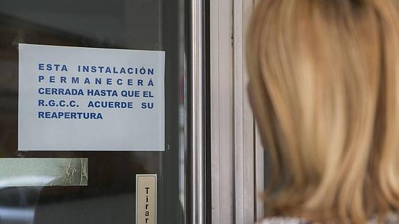 Una mujer lee el cartel colocado en la puerta del Centro en el paseo de Begoña una vez cerrado.