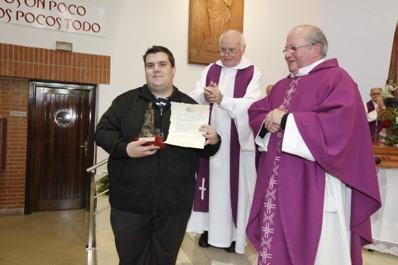 Christian Guisado recibe el galardón de las manos de Fernando Fueyo y de José María Lorenzo, arcipreste de Oviedo.