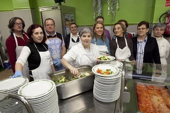 Responsables y voluntarios de la Cocina Económica, preparados para servir decenas de platos en el comedor social de la entidad, ubicada en la calle de Mieres. 