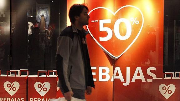 Un hombre pasa frente a un cartel de rebajas en un centro comercial asturiano.