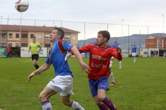 El ariete del TSK Roces Javi Manín pugna por el balón con Dani Hevia en el último derbi en La Cruz ante el Ceares. 