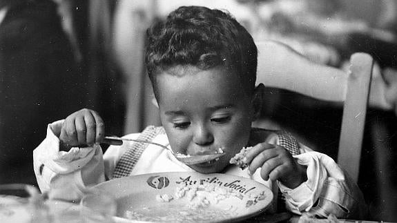 Un niño come en un hogar del Auxilio Social durante la postguerra.