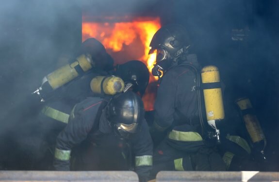 Bomberos durante la práctica de 'flash over' en el interior de una edificación incendiada, en el Centro de Seguridad Integral Jovellanos. 