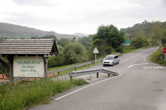 En primer término un cartel instalado por el Ayuntamiento de Herrerías en el límite del municipio y al fondo otro indicando la entrada al Principado de Asturias. 