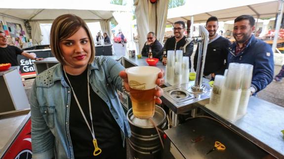 La camarera de uno de los puestos muestra un vaso de cerveza. 