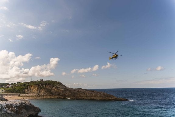 El helicóptero de Servicio de Emergencias del Principado sobrevuela la playa de El Sablón en busca del nadador desaparecido. 