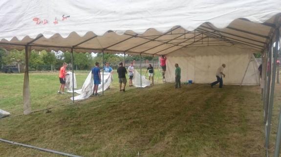 Numerosos voluntarios de la parroquia colaboran en la instalación de la carpa.