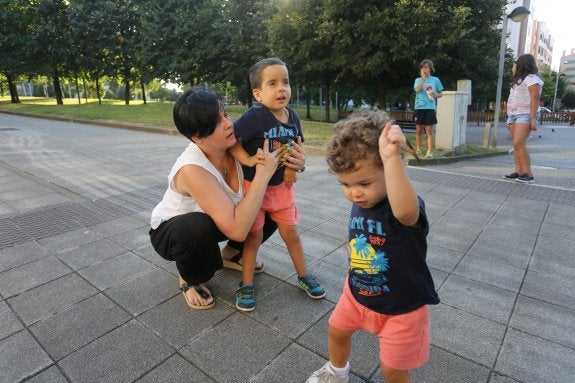 Eva Brandi sujeta a su hijo mayor, Kike, mientras el pequeño Izan juega con un palo, en el parque de Montevil. 