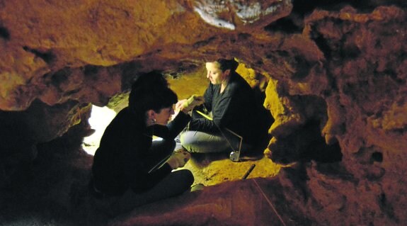 Dos personas trabajando en las excavaciones de la Cueva del Olivo, de Pruvia. 