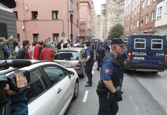 Numerosas personas se agolpan junto a los vehículos policiales en la calle Rosalía de Castro de Gijón, donde se llevó a cabo el operativo antiyihadista. 