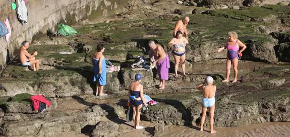 Las altas temperaturas animaron al baño en la playa gijonesa de San Lorenzo. Un grupo de bañistas se seca al sol en el pedreru bajo el Campo Valdés. 