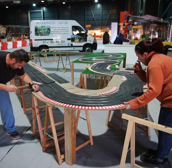 Dos operarios instalan un circuito de scalextric gigante. 