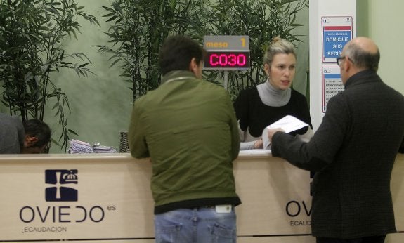 La trabajadora Yolanda Zamora atiende a dos ovetenses. 