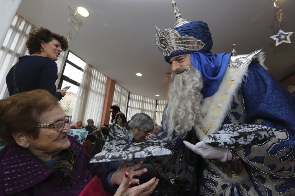 Melchor entrega un regalo a un anciano en un centro de la tercera edad de Avilés 