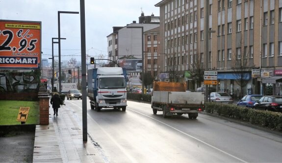 Dos camiones circulando por el casco urbano de Lugones. 