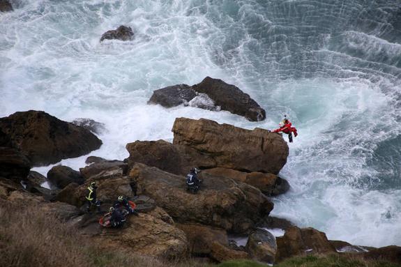 El rescatador del Helimer desciende a las rocas sobre las que el herido está siendo atendido por los bomberos. 