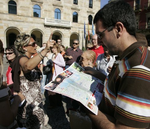 Una guía se dirige a un grupo de turistas en Gijón 